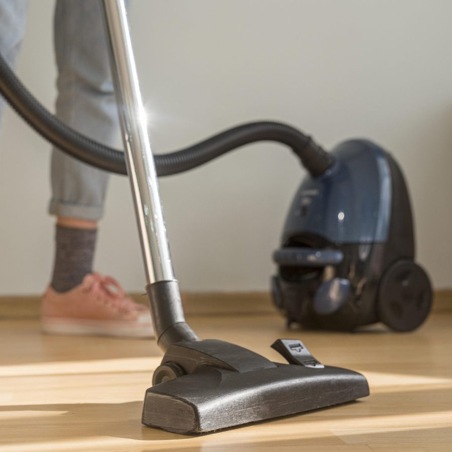 Aspirador horizontal tipo cilindro com tubo e mangueira limpando embaixo da cama